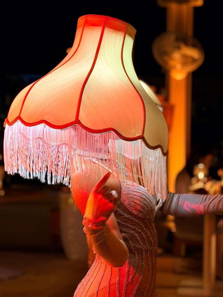 Circensia private event performer beneath a fringed lamp