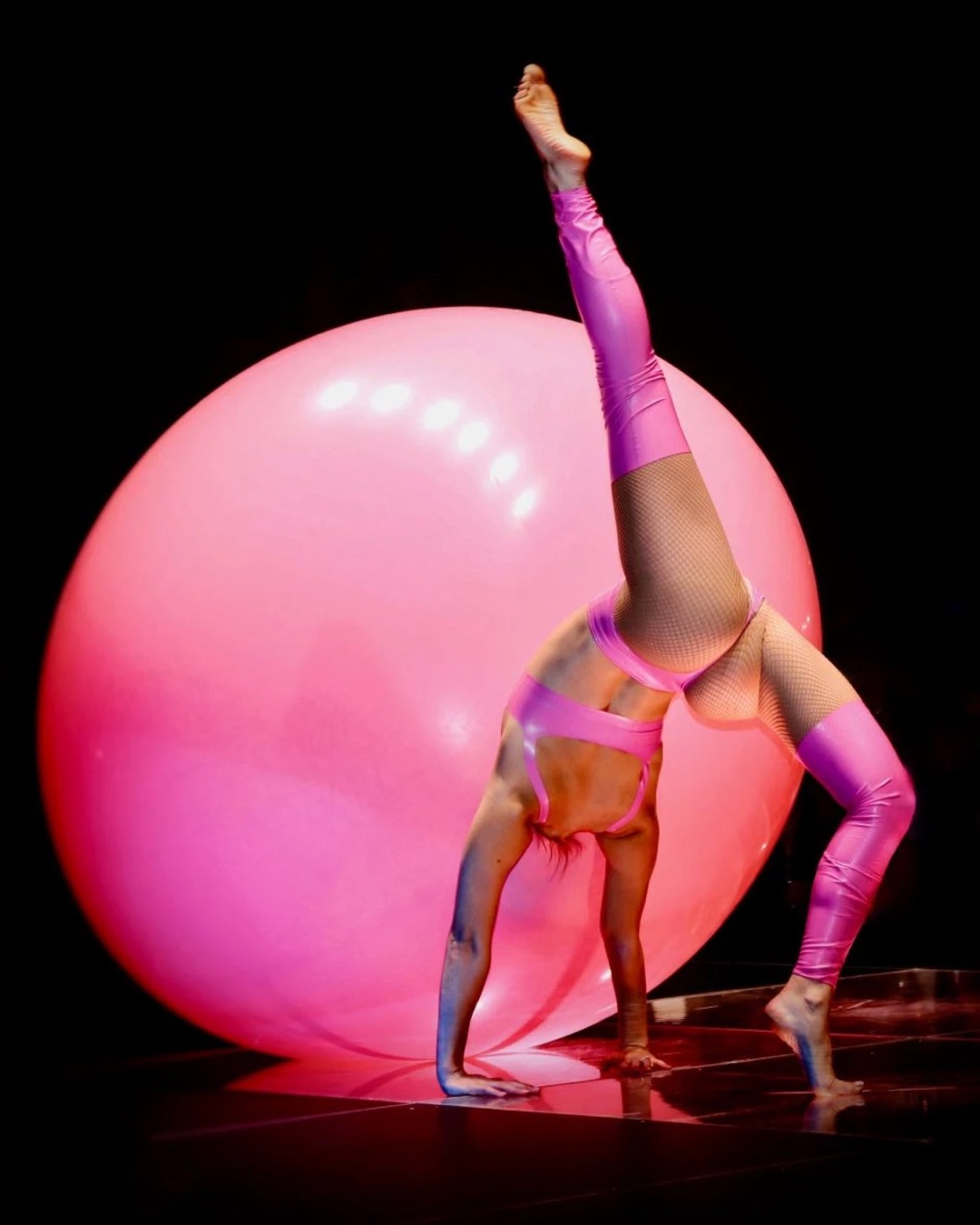 Circensia acrobat performing beside an illuminated pink sphere